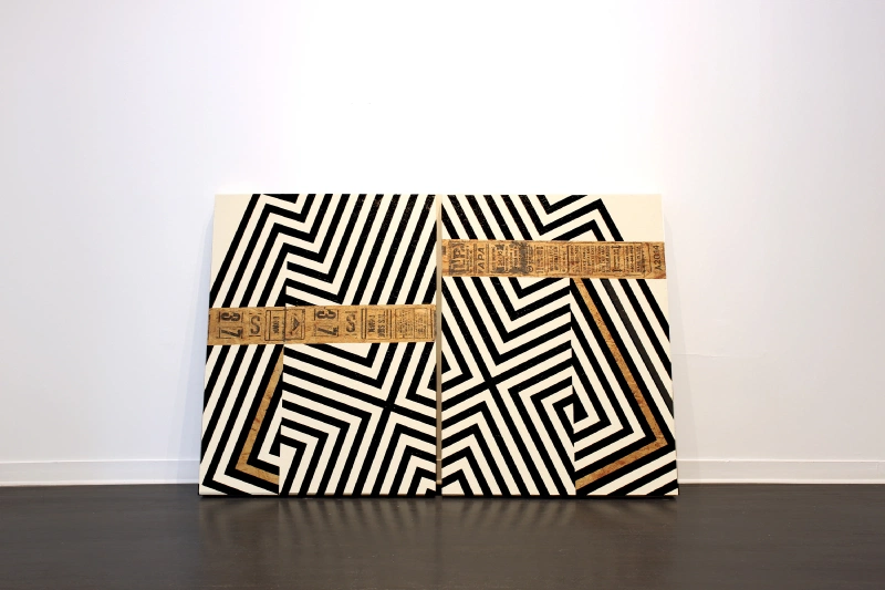 Black-and-white striped sculptural painting with tan collage bands leaning against a white wall.